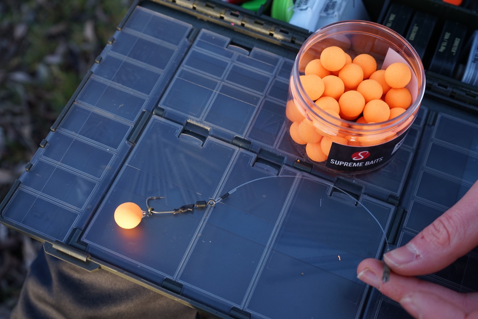 Pop-Up-Rig auf der Tacklebox, daneben eine Dose mit orangen Pop-Ups